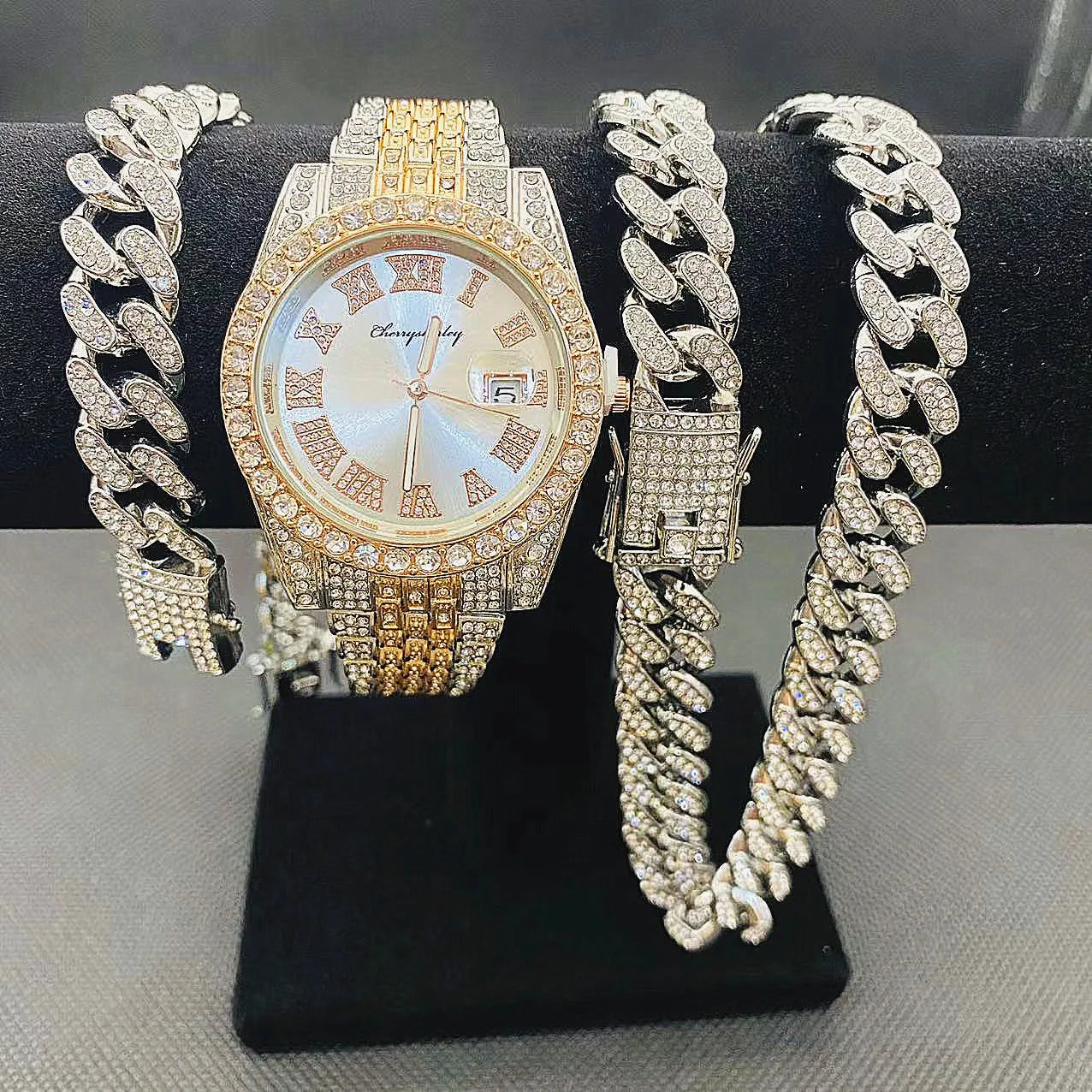 Gold watch with diamond-encrusted chain on a black stand