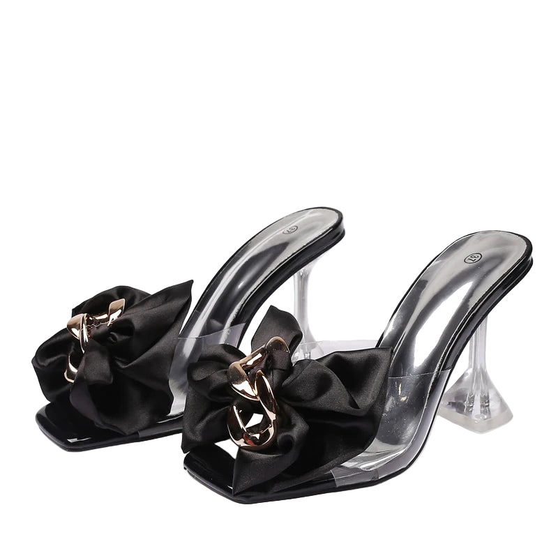 Black high-heeled shoes with clear soles and decorative bows