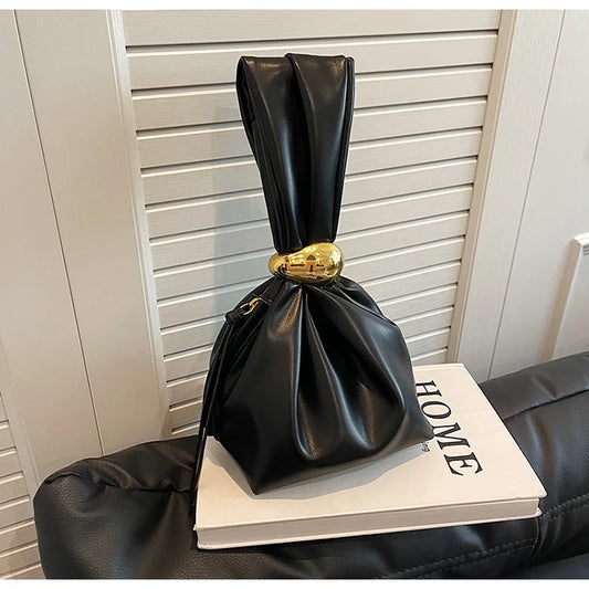 Black leather bag with a gold buckle on top of a book titled 'HOME'.