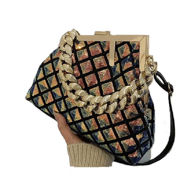 Multicolored patterned handbag with gold chain strap held by a hand on a white background