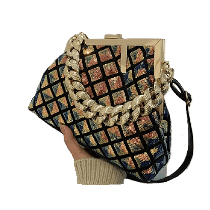 Multicolored patterned handbag with gold chain strap held by a hand on a white background