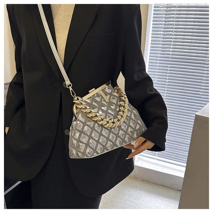Person wearing a black blazer holding a patterned handbag with gold chain detail.