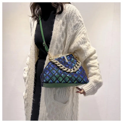 Person wearing a blue and green patterned handbag with a white cardigan.