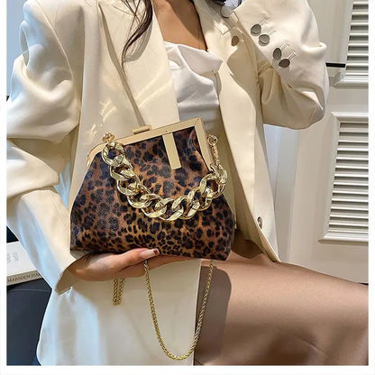 Person holding a Carauana_UNIU_Leopard_Clutch with gold chain detail