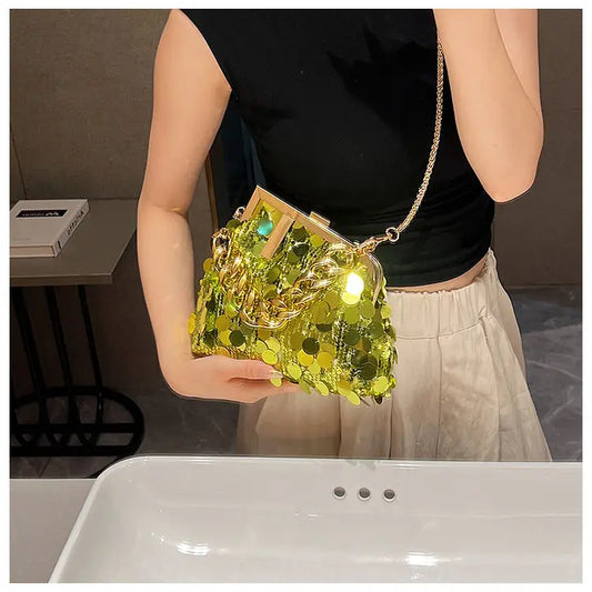 Person holding a green sequin handbag in an indoor setting