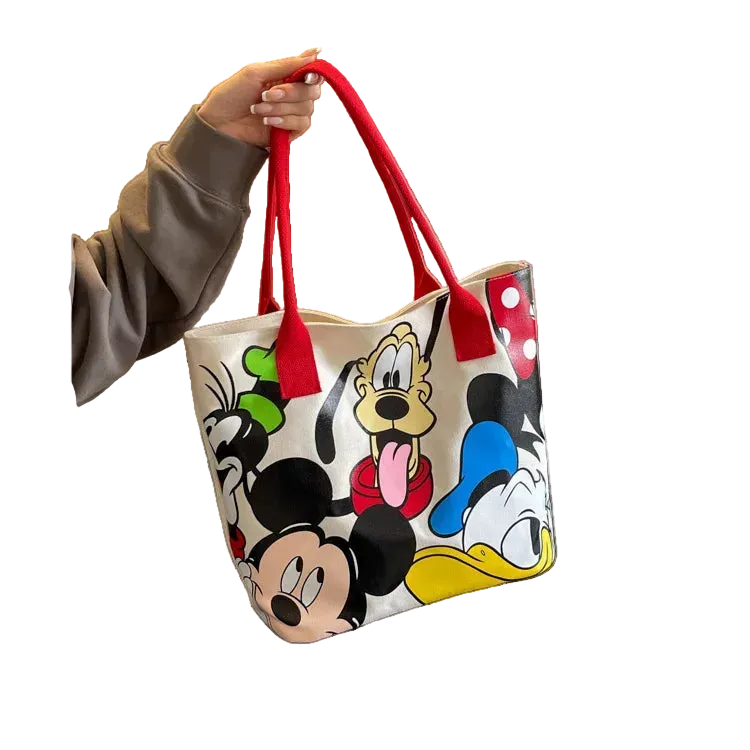 Tote bag with cartoon character designs held by a person, placed on a surface.