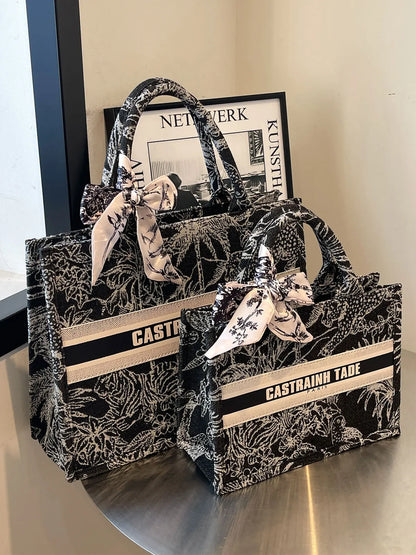 Two black and white patterned handbags with 'Castrain Tae' branding on a reflective surface.